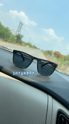 a pair of sunglasses sitting on the dashboard of a car that says saturday in blue lettering