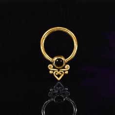 a gold ring with a black stone in the shape of a heart and an eye