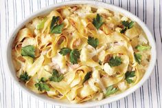 a white bowl filled with pasta covered in cheese and parsley