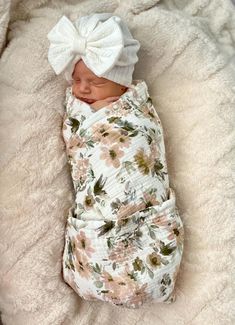 a newborn baby wrapped in a blanket with a big bow on it's head