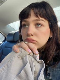 a woman sitting in the back seat of a car with her hand on her chin