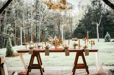 a wooden table topped with plates and bowls filled with flowers sitting on top of a lush green field