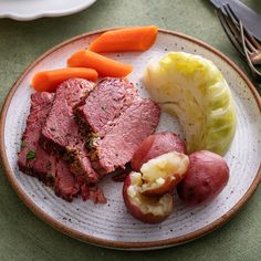 a white plate topped with meat, potatoes and carrots on top of a table