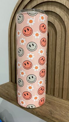 a pink and white flowered pattern with smiley faces on it is next to a wooden wall