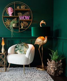 a living room with green walls, gold accents and flamingos on the side table