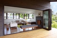 an open living room and dining area with wood flooring on the outside, overlooking trees