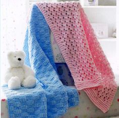 a white teddy bear sitting next to a blue and pink blanket