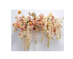 an arrangement of flowers on a white wall with long stems and small flowers in the center