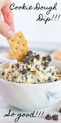 a hand dipping a cracker into a bowl of cookie dough dip with chocolate chips