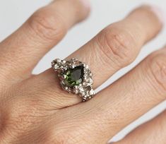 a woman's hand with a ring on it and a green stone in the middle