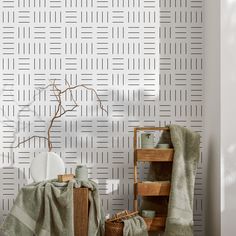 a room with white wallpaper and green towels on the table next to a wooden shelf