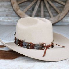 The Rowan Western Feather Hat Band, Short, is specially crafted for smaller-sized hats (6 7/8 and under) and kids' hats. Made from 100% feather, it has an approximate length of 53 cm (excluding leather ties) and a width of 2 cm. The crest measures 4" W x 3.25" H, adding a distinctive and elegant touch to the design. Adjustable with leather ties, this hat band ensures a secure fit while providing a stylish western accent for smaller hats. Feather Hat Band, Beaded Hat Bands, Kids Belt, Beaded Hat, Feather Hat, Pets For Sale, Boy Hat, Cowboy Boots Women, Leather Hats