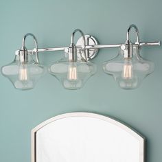 three light bathroom fixture with clear glass shades on the top and bottom lights in chrome finish