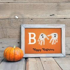 an orange pumpkin sitting on top of a wooden table next to a sign that says boo happy halloween