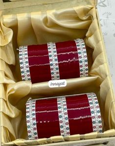 two rolls of red ribbon in a box with gold trimmings on the sides