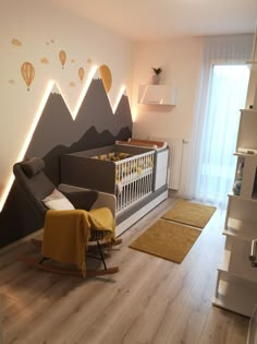 a baby's room with mountains and hot air balloons on the wall