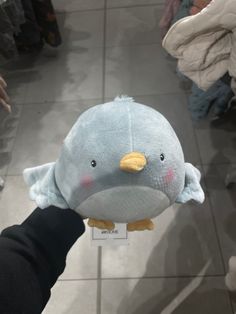 a person holding a stuffed animal in the shape of a blue bird with yellow beak