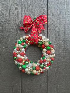 a christmas wreath hanging on the side of a wooden door with red and green ornaments