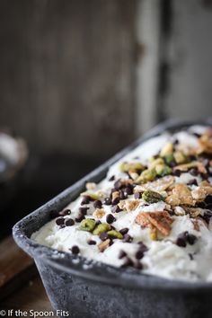 an ice cream dish with chocolate chips and pistachios in it on a wooden table