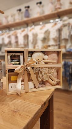 a wooden box filled with dolls on top of a table in front of some shelves