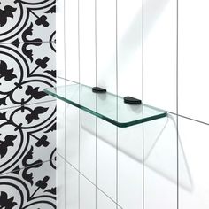 a glass shelf in the corner of a room with black and white tiles on it