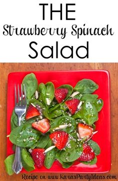 a red plate topped with spinach and strawberries next to a knife and fork