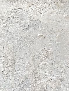 an old white stucco wall with cracks in it