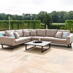 a large sectional couch sitting on top of a stone floor next to a swimming pool