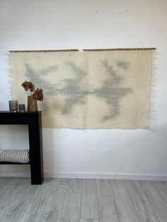 a table with vases on top of it next to a wall hanging