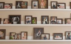 many different frames are arranged on the wall in this family's photo gallery area