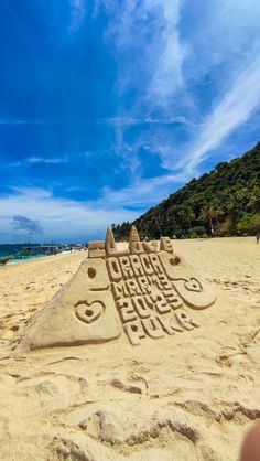 a sand castle made to look like a fish with words written in it on the beach