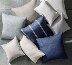 many pillows are arranged on the floor and one is white, blue, gray and black