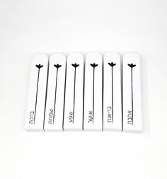 four white matchesticks with black flowers on them sitting next to each other in front of a white background