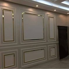 an empty room with white walls and gold trim around the edges, along with a black door