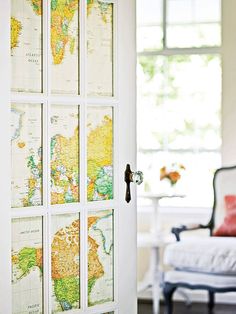 an open door with maps on it in front of a white couch and window sill