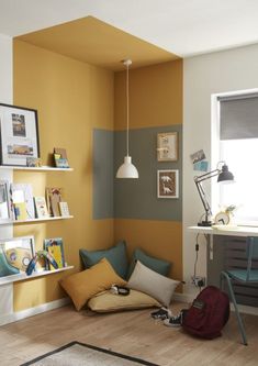 a living room with yellow walls and blue chairs in the corner, bookshelves on the wall