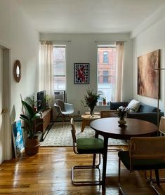 a living room filled with furniture and lots of windows next to a wooden floor covered in plants