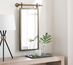 a wooden table topped with a mirror next to a lamp