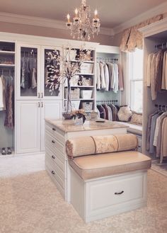 a walk in closet filled with lots of clothes and drawers next to a chandelier