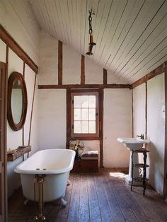 an old fashioned bathtub and sink in a bathroom with wood floors, white walls and ceiling