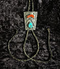 Vintage Viola Calavaza Sterling Silver Turquoise Bolo Tie in a Navajo Design. The sterling silver centerpiece measures approximately 3" x 2". Vintage from the 1960s, includes turquoise and coral. It is missing the metal tips that are usually on a bolo tie, but actual silver piece is in good condition. Silver Turquoise Western Necklace For Festivals, Southwestern Silver Turquoise Necklace For Festival, Western Silver Turquoise Necklace With Concho, Vintage Hand Tooled Jewelry For Western-themed Events, Vintage Hand-tooled Jewelry For Western-themed Events, Vintage Blue Turquoise Necklace With Concho, Handmade Western Silver Turquoise Necklace, Silver Southwestern Turquoise Necklace For Western Events, Southwestern Silver Turquoise Necklace For Western Events