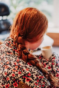 a woman sitting at a table with a cup of coffee in her hand and looking down