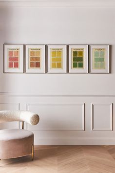 a living room with white walls and four framed color samples on the wall above a chair