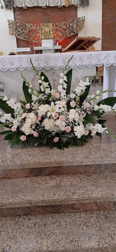 flowers and greenery are placed on the steps in front of a church alterpiece