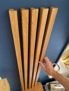 a hand is reaching up to the side of a wooden chair with wood slats on it