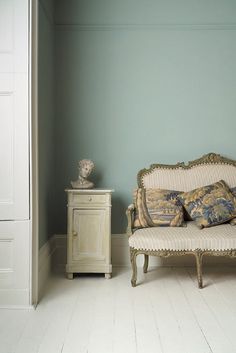 a white couch sitting on top of a wooden floor next to a cabinet and lamp