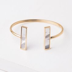 This bangle is the perfect gift to anyone you are trying to impress. Lightweight enough so it's comfortable to wear all day but with incredible mother-of-pearl detail that makes this piece a statement. Materials: 14k gold plated stainless steel and mother-of-pearl bracelet. Size: 7.5 inches Hypoallergenic; lead and cadmium free with nickel content less than 100 ppm. Box Size: Medium Mother Of Pearl Bangle Jewelry Gift, Mother Of Pearl Bangle For Gift, Elegant Bangle Bracelet In Mother Of Pearl, Elegant Adjustable Mother Of Pearl Bracelet, Modern Gold Pearl Bracelet As Gift, Chic Gold-tone Bangle As Gift, Mother Of Pearl Oyster Bracelet Gift, Elegant Brass Bangle As Gift, Elegant Brass Bangle For Gift