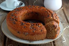 a bundt cake on a plate next to a cup and saucer with milk