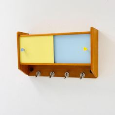 a wooden shelf with hooks and two colored sticky notes on it