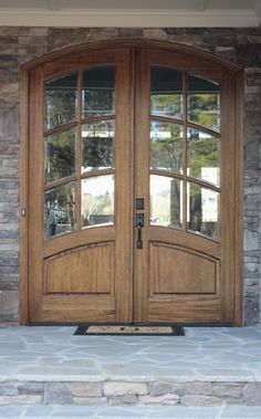 a pair of double doors with glass on the top and bottom, in front of a stone building